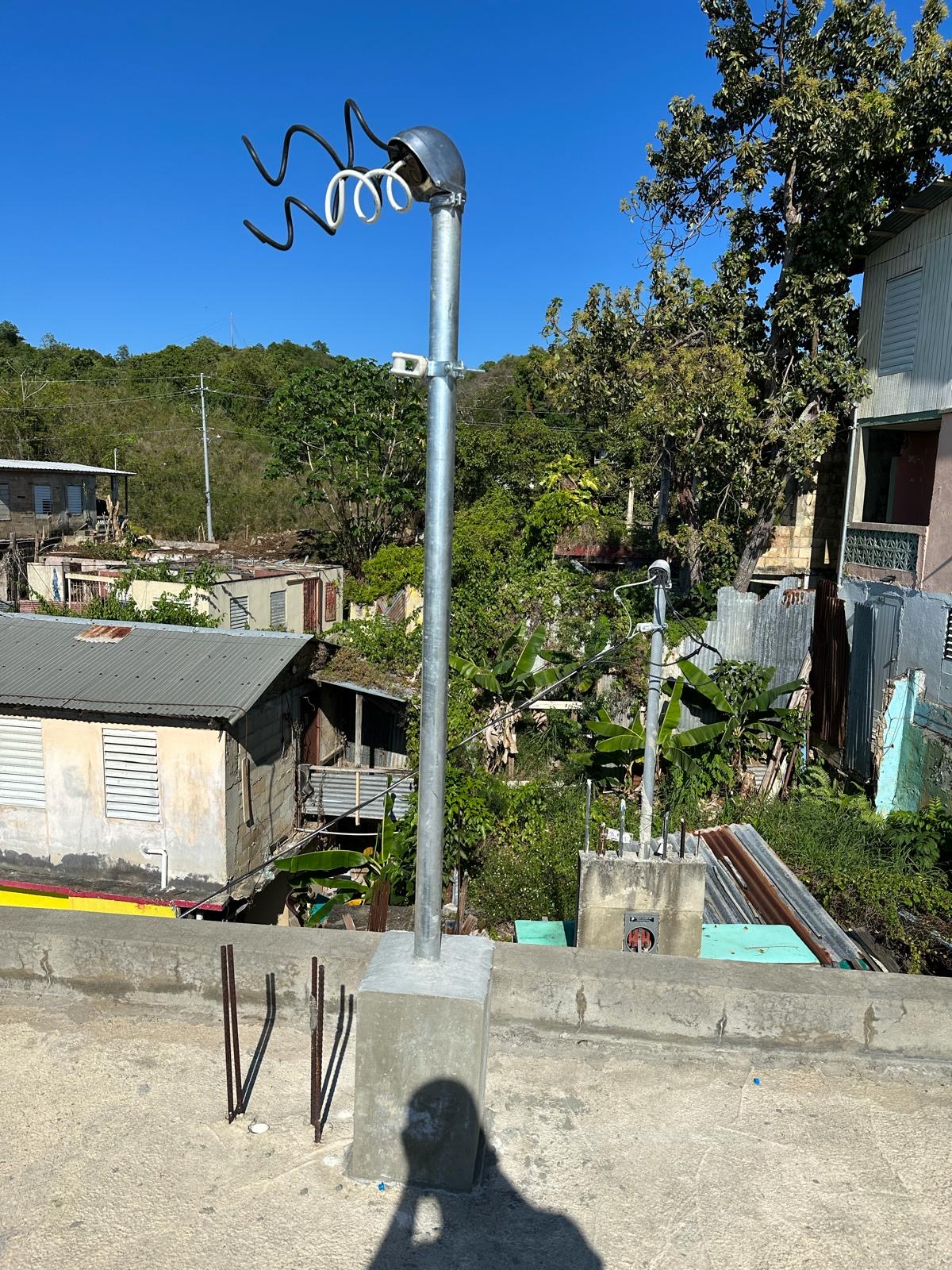 Galvanized service mast and riser set in a new concrete base, with drip loops on the service conductors